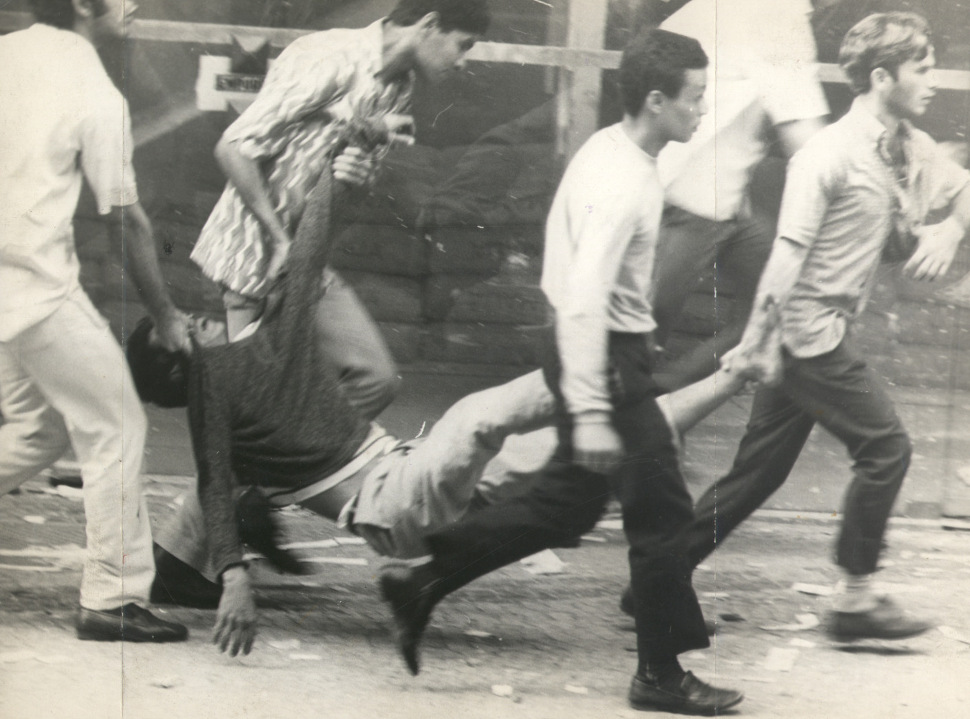 A wounded man being carried by four others.